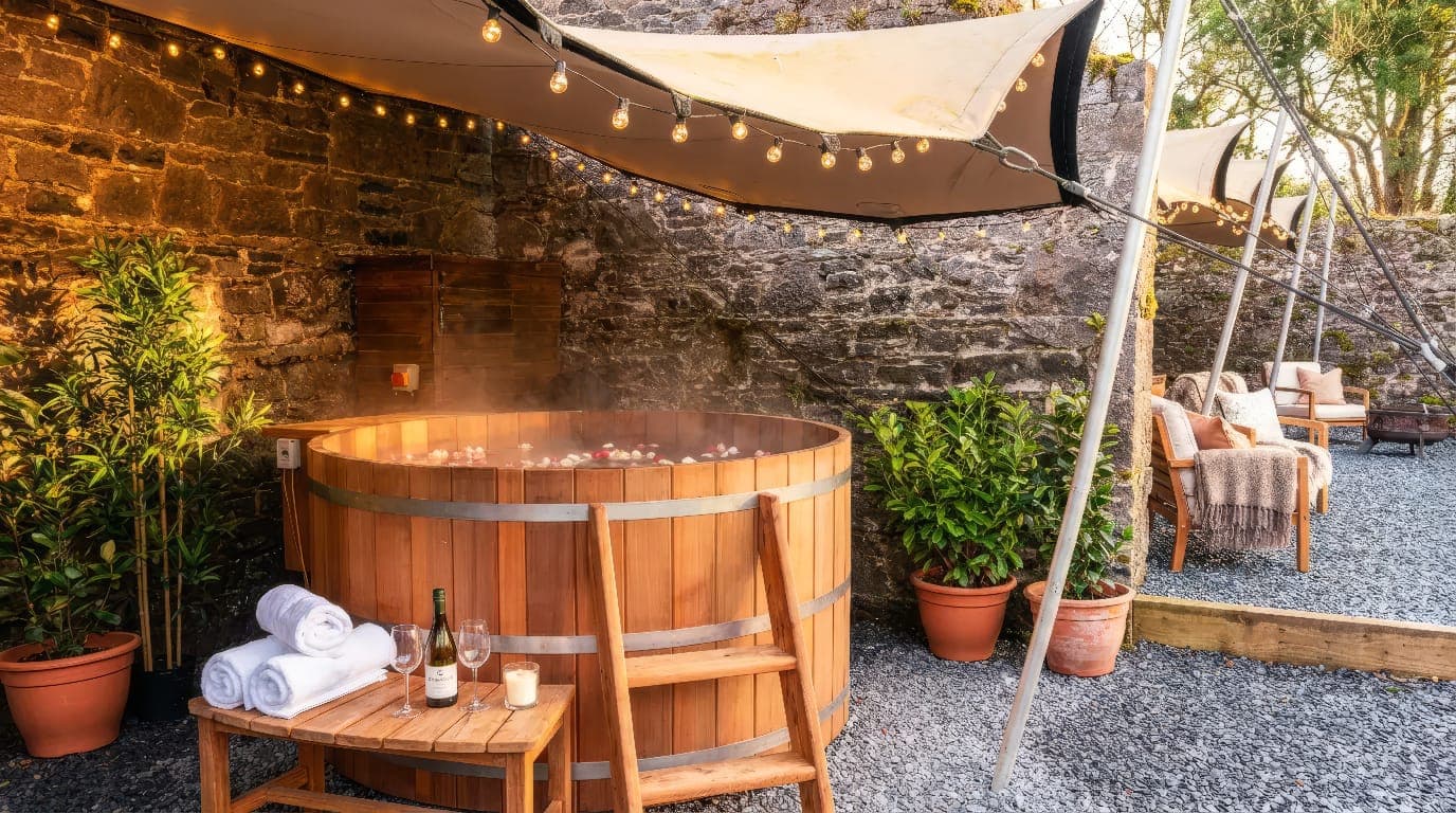 Der holzbefeuerte Zedernholz-Hot-Tub auf Ballinderry Park in einem ummauerten Innenhof mit Lichterketten