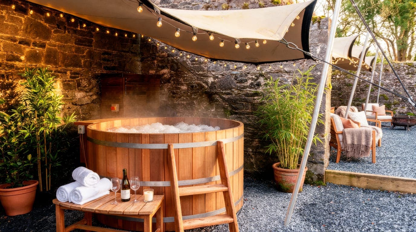 The wood-fired cedar hot tub steaming in the walled courtyard at golden hour